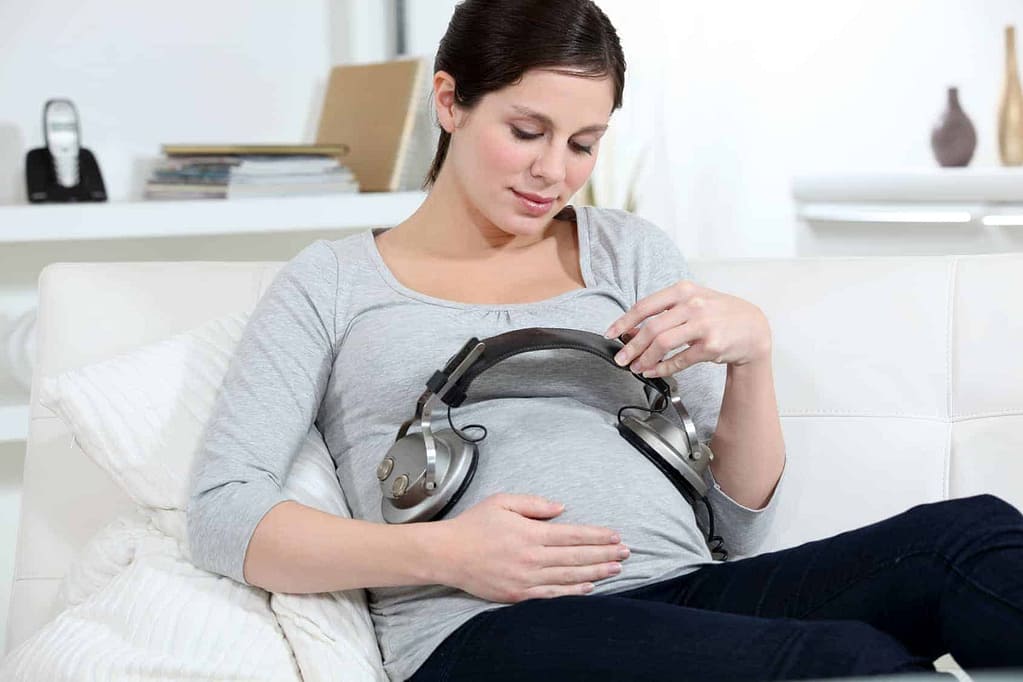 Schwangere Frau mit Kopfhörern am Babybauch