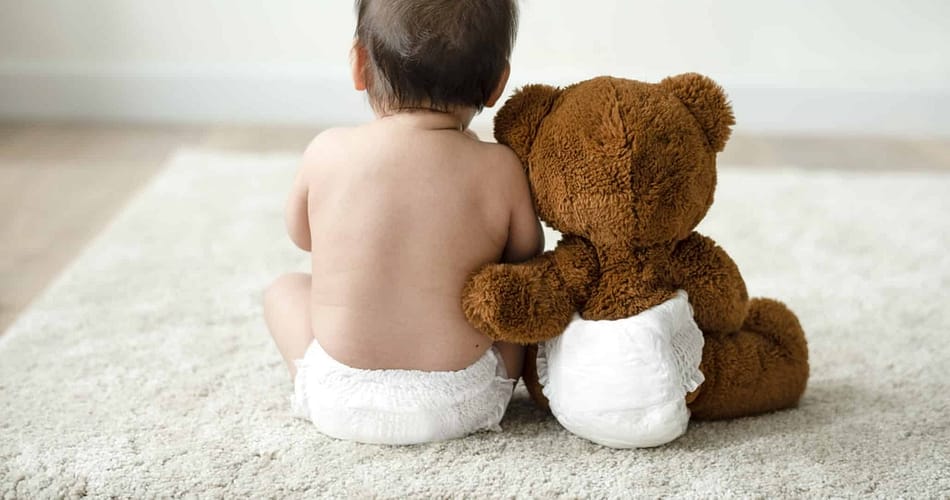 Baby und Teddybär in Windeln